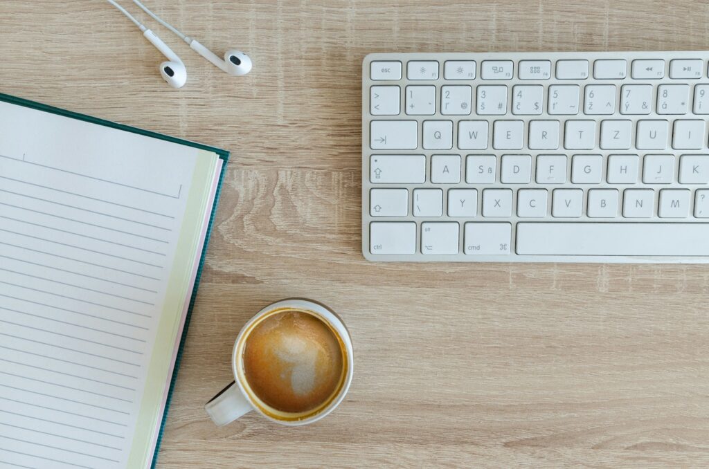 Photo by Lukas Blazek coffee latte near white wireless keyboard and Apple EarPods on the table photography